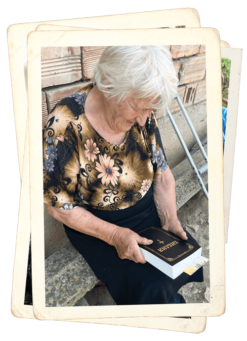 an elderly woman smiles down at a new Bible